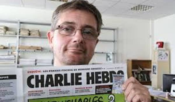 Le défunt Charb montrant une "Une" de Charlie Hebdo.