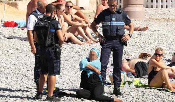 Des policiers en train de verbaliser une femme sur une plage de Nice.